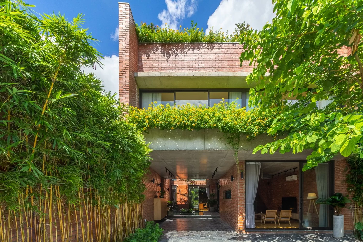 Tường bao xung quanh không gian xanh được xây bằng gạch không trát mang đến cảm giác giản dị, vững chắc và phù hợp với miền nhiệt đới