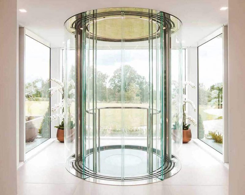 Mẫu thang máy lồng kính Panorama hiện đại lắp đặt tại giếng trời biệt thự Vinavic, vách kính cường lực trong suốt, khung thép đen tinh tế, tạo điểm nhấn kiến trúc.