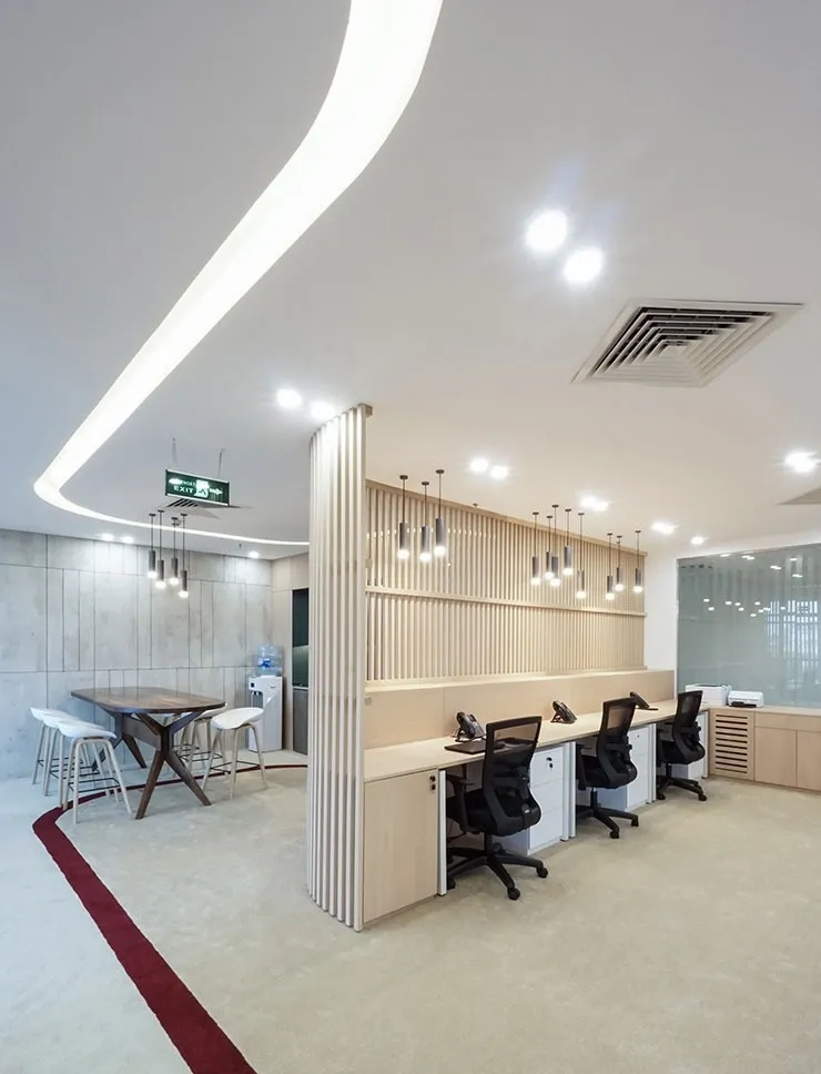 Hành lang văn phòng rộng rãi với mảng tường trắng lớn, chỉ có một băng ghế chờ, nhấn mạnh việc sử dụng không gian âm trong thiết kế văn phòng tối giản.