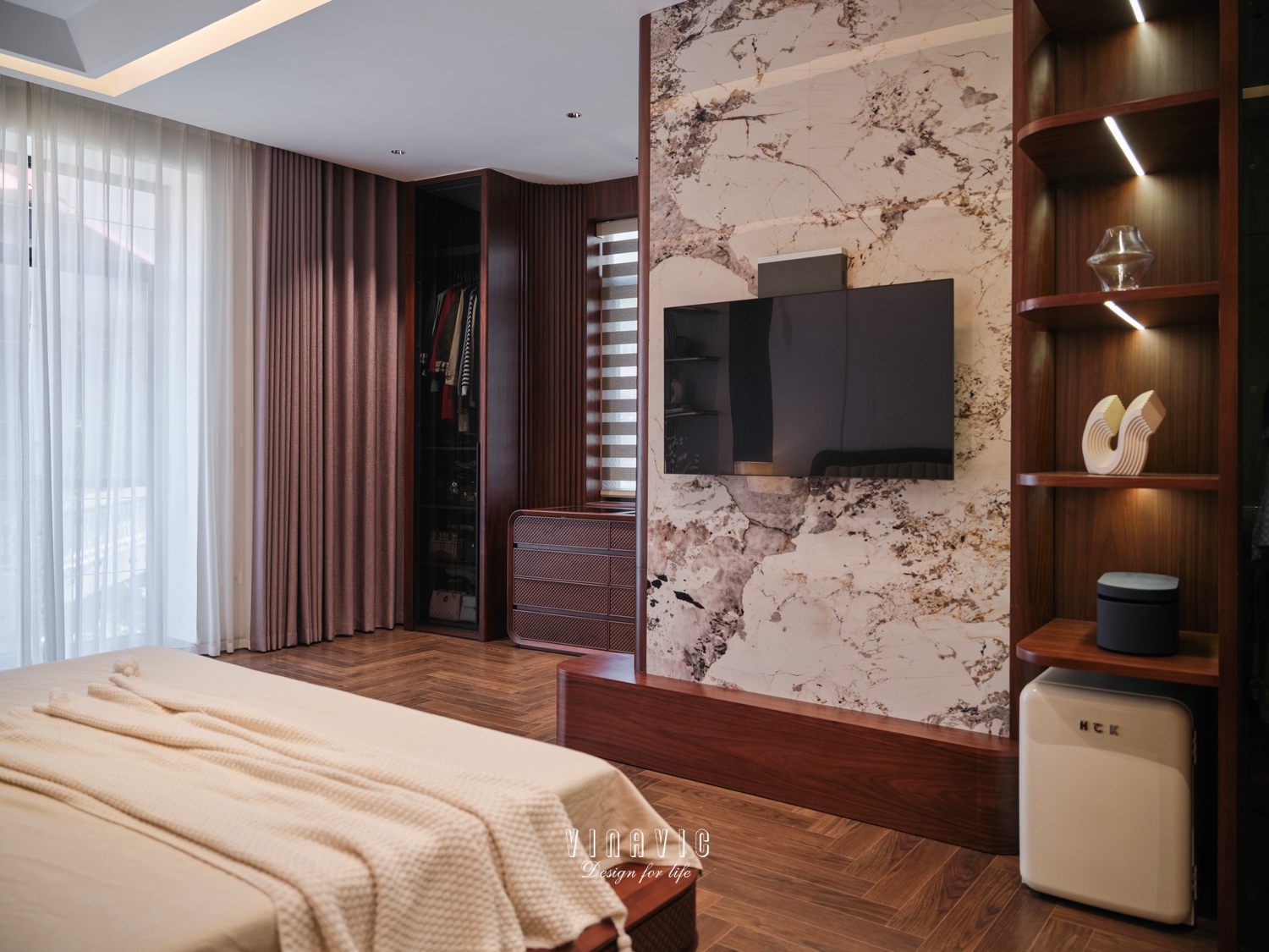 Kệ tivi đối diện giường kết hợp với mảng đá vân lớn và hệ kệ trang trí, tạo điểm nhấn thị giác rõ nét cho căn phòng